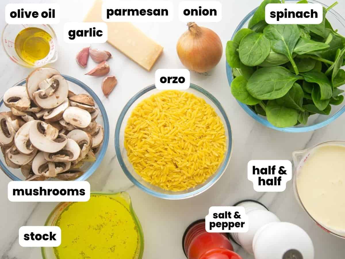 The ingredients needed to make mushroom orzo with spinach. on a marble counter, labeled with white text boxes.