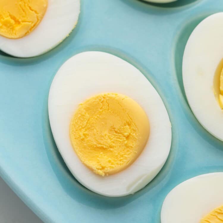 Perfect hard boiled eggs on a blue plate, perfect yellow yolks and set whites.