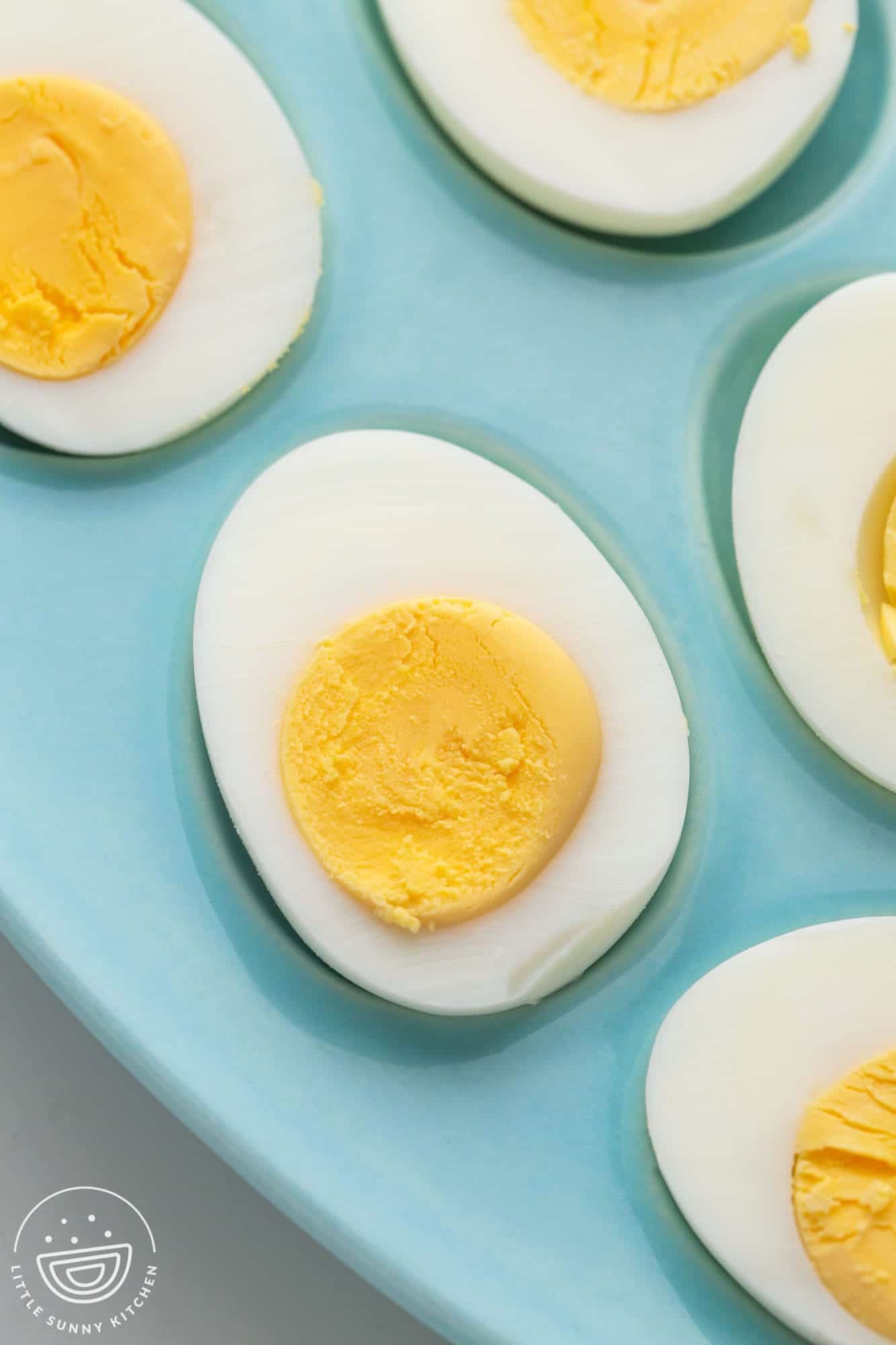 Perfect hard boiled eggs on a blue plate, perfect yellow yolks and set whites.