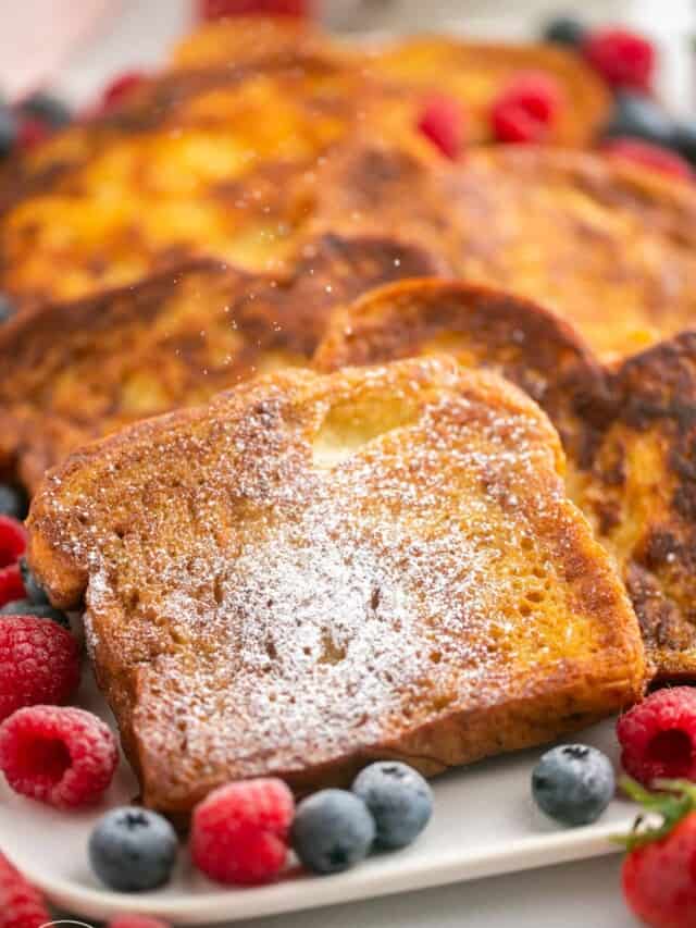 French toast dusted with powdered sugar on a platter with berries.