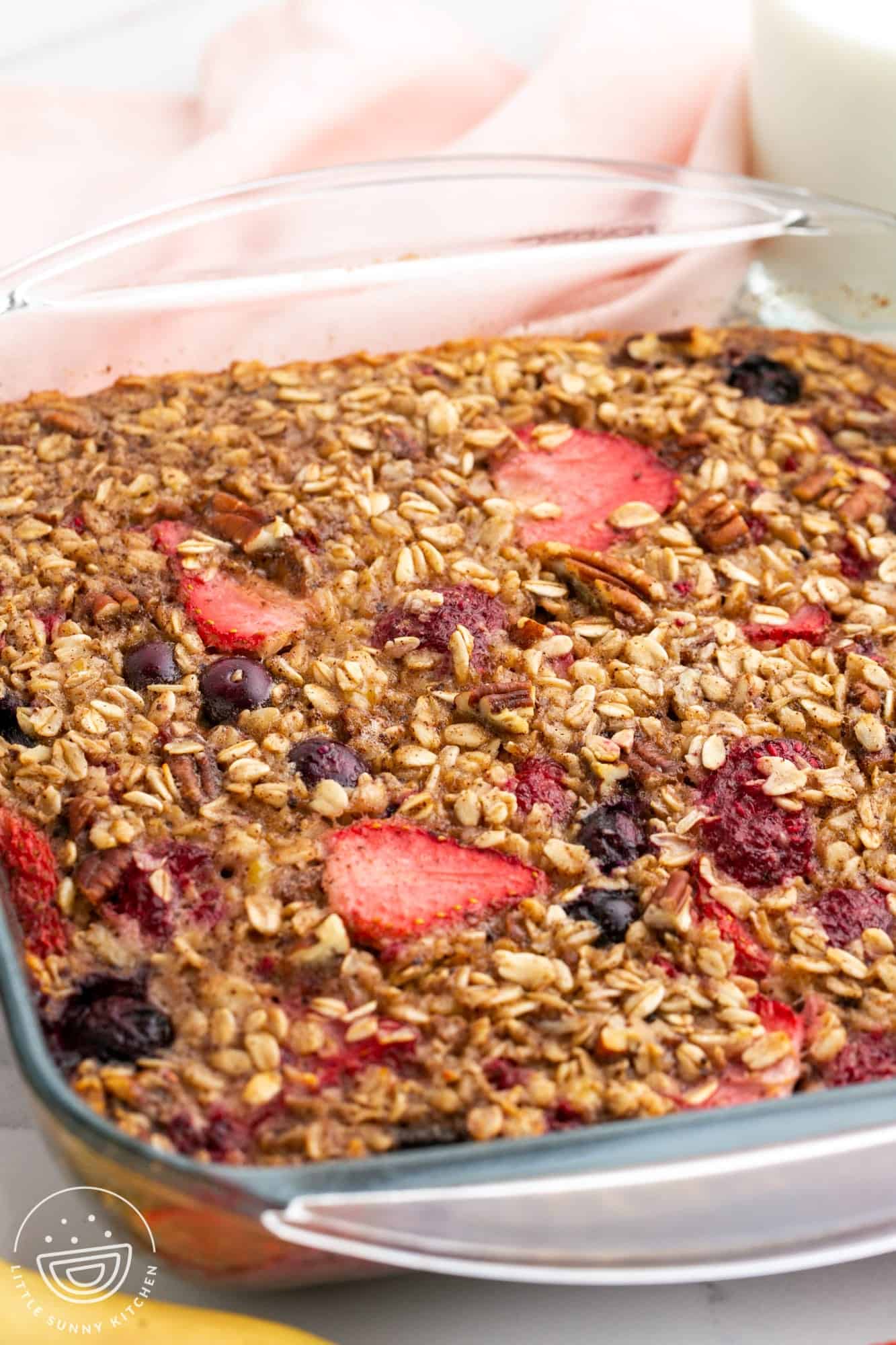 Baked oatmeal in a square pan, topped with strawberries and raspberries.