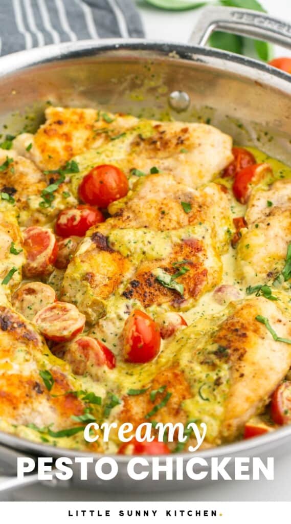 creamy pesto chicken in a metal skillet with cherry tomatoes.