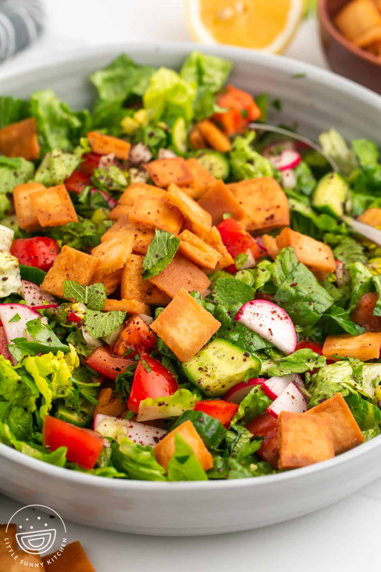 a large white bowl filled with fattoush salad. 
