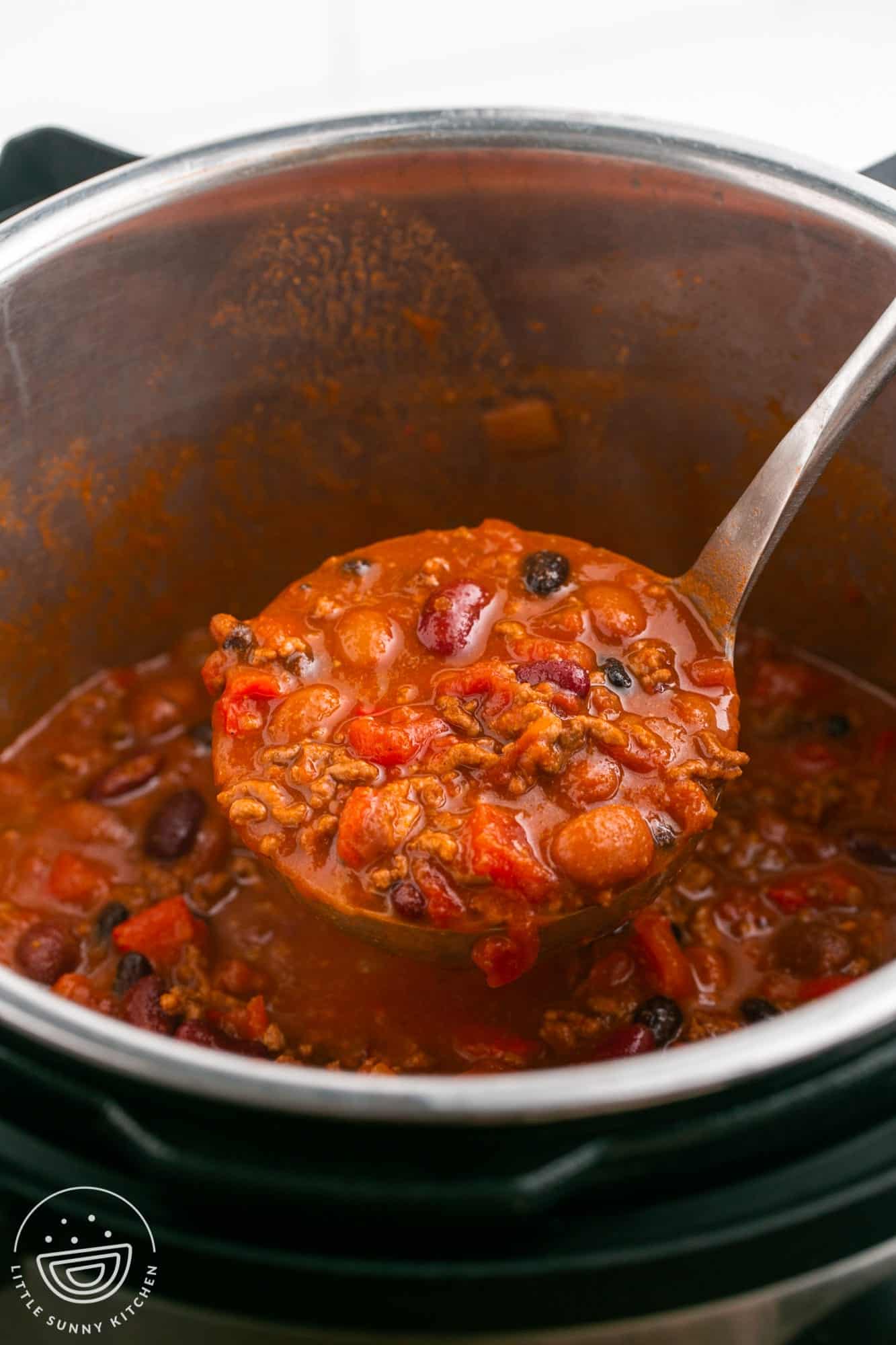 a ladle bringing chili out of an instant pot.