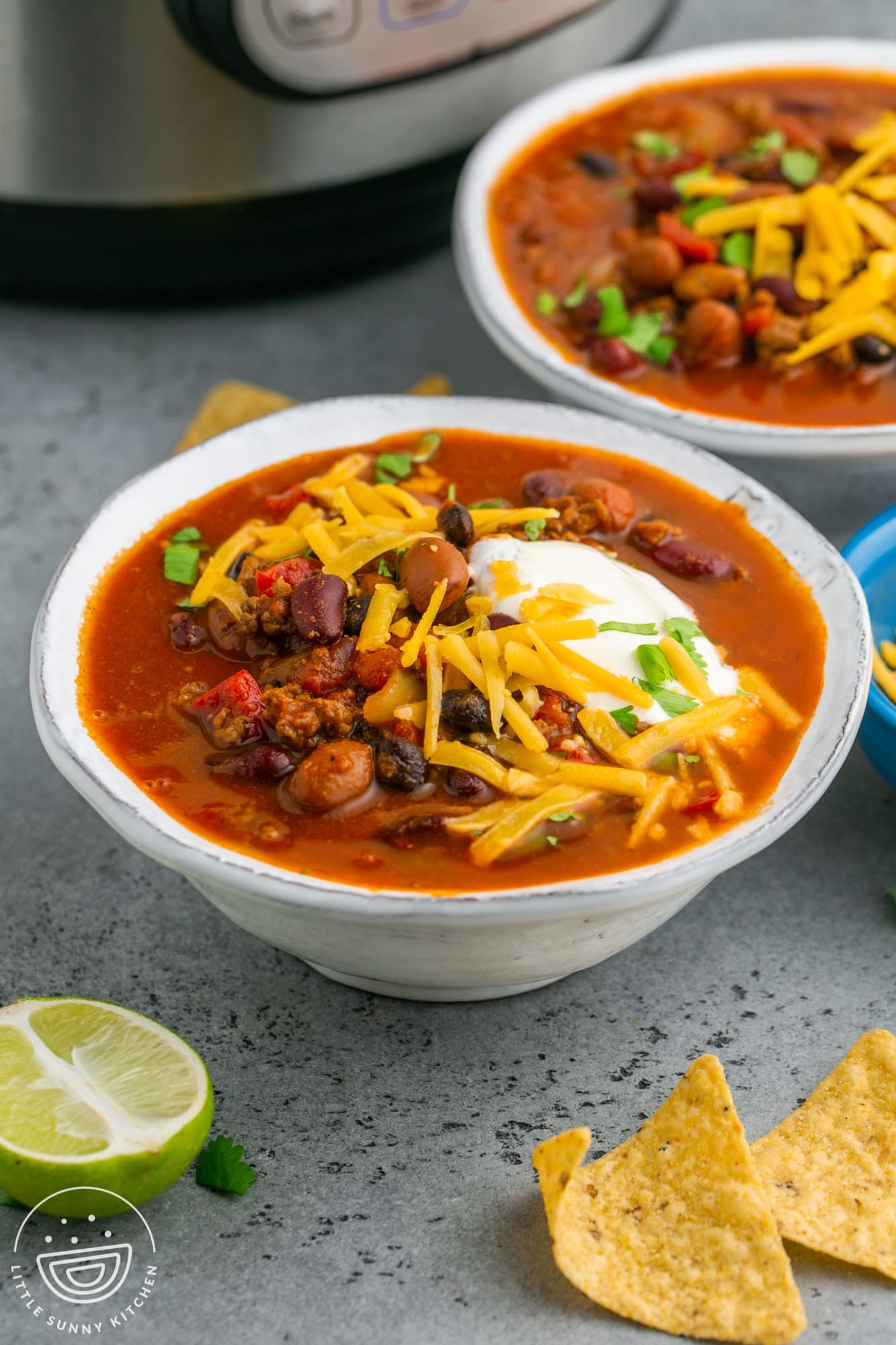 two bowls of chili in front of an instant pot.
