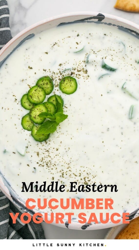 Overhead shot of khyar bi laban, or cucumber yogurt sauce in a large bowl, with kalmata olives on the side and pita chips. And overlay text that says "Middle Eastern Cucumber Yogurt Sauce"