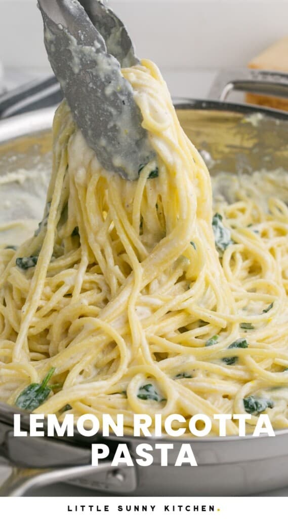 tongs holding up spaghetti with lemon ricotta sauce in a skillet.