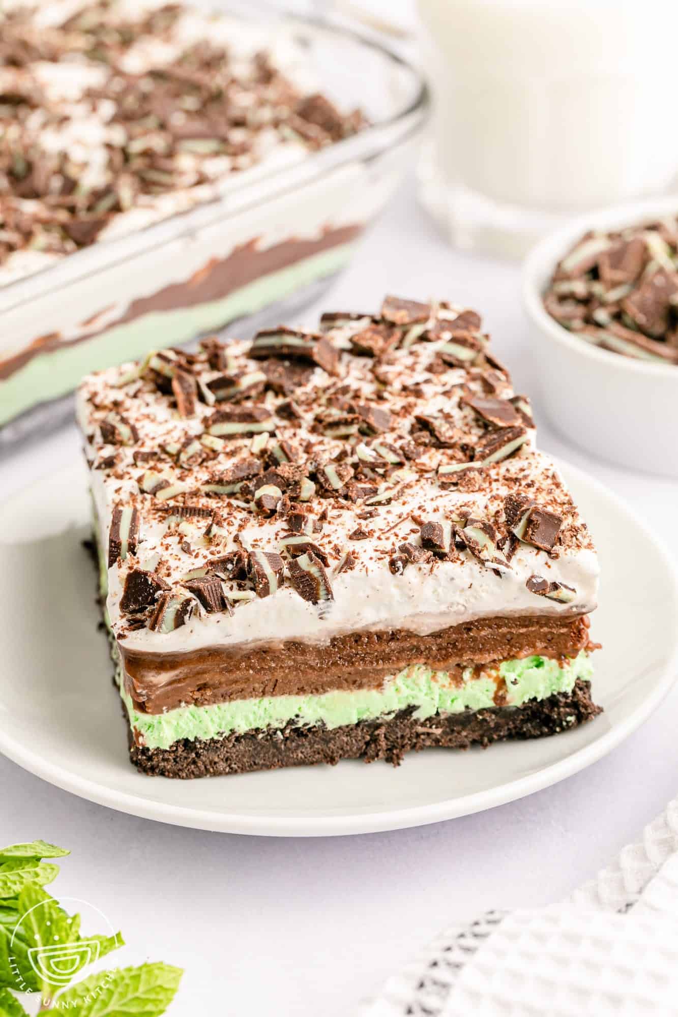a square piece of chocolate lasagna with layers of oreo crumbs, mint pudding, chocolate pudding, and whipped topping. 