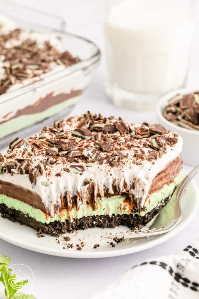 a large slice of mint chocolate lasagna with a bite taken from the front corner. there is a fork on the right side of the plate.