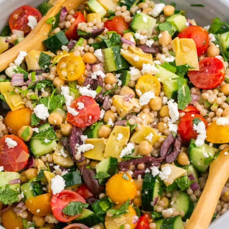 a salad of pearl couscous, tomatoes, and feta cheese, in a large salad bowl.