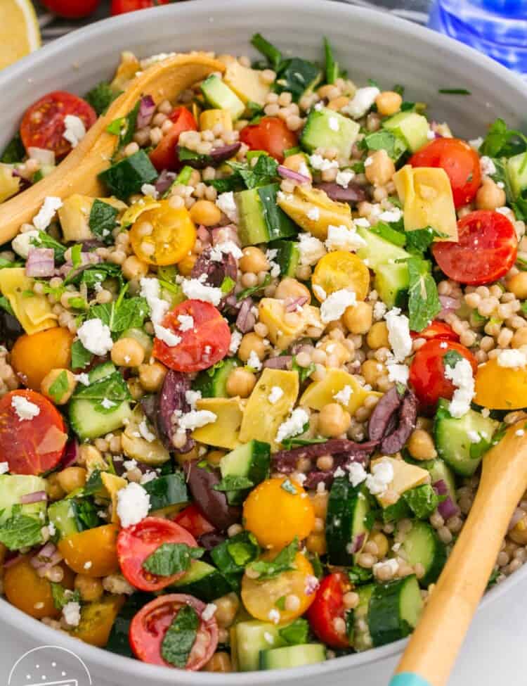 a salad of pearl couscous, tomatoes, and feta cheese, in a large salad bowl.