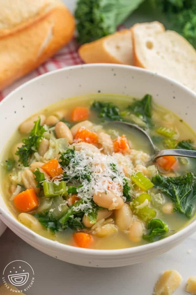 a single serving of white bean soup in a ceramic white bowl, topped with parmesan cheese.