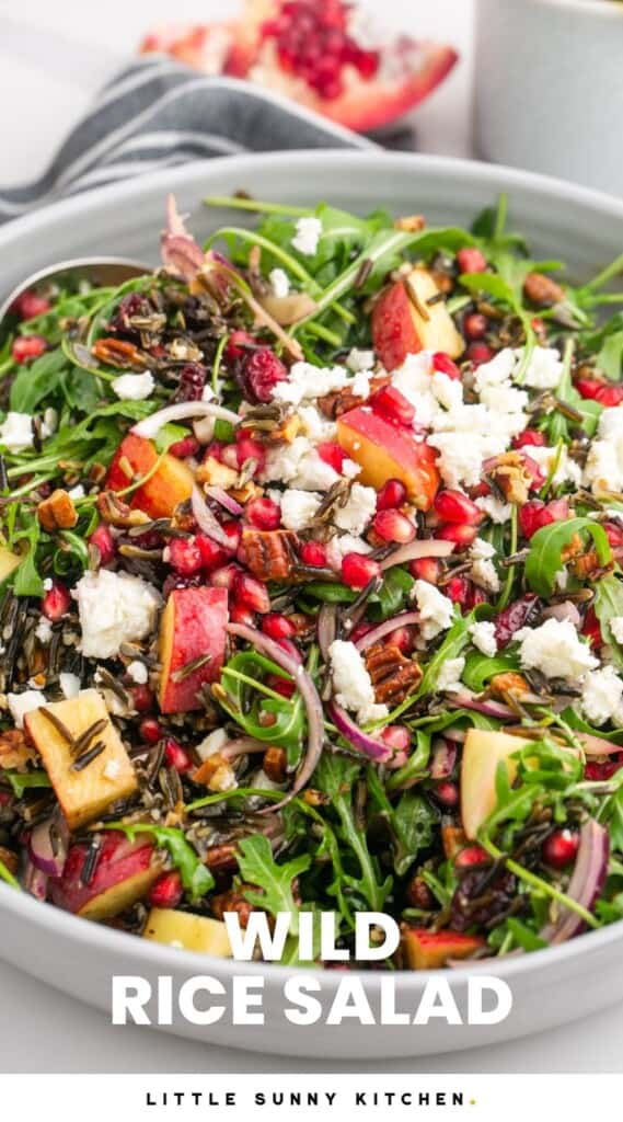 a large bowl of salad with wild rice, fruit, feta, and dressing. Text overlay at bottom of image says "wild rice salad"