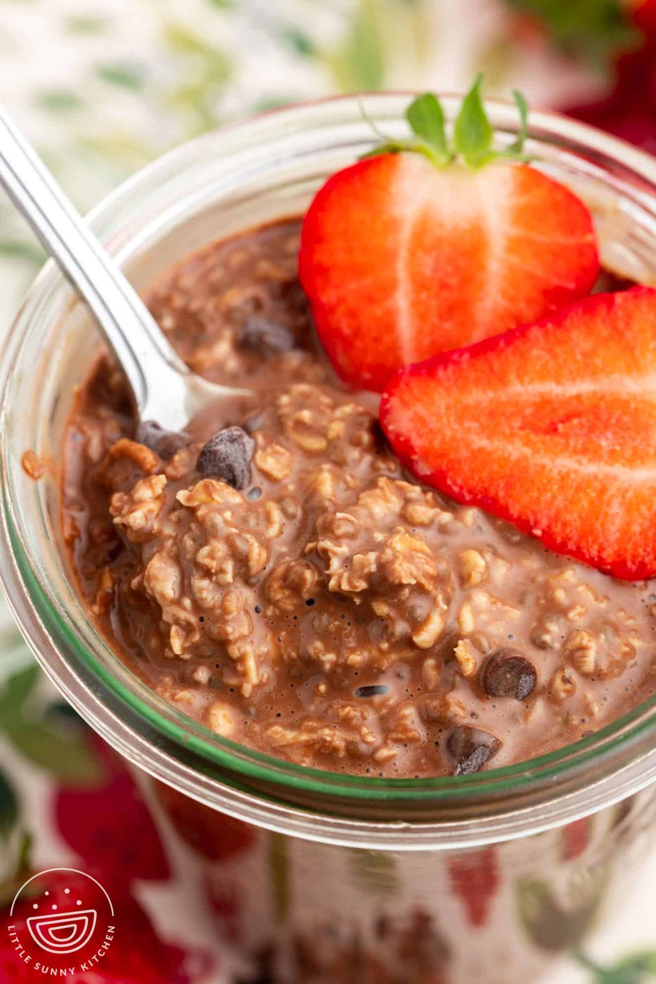 closeup of a jar of chocolate oatmeal with chocolate chips and strawberries.