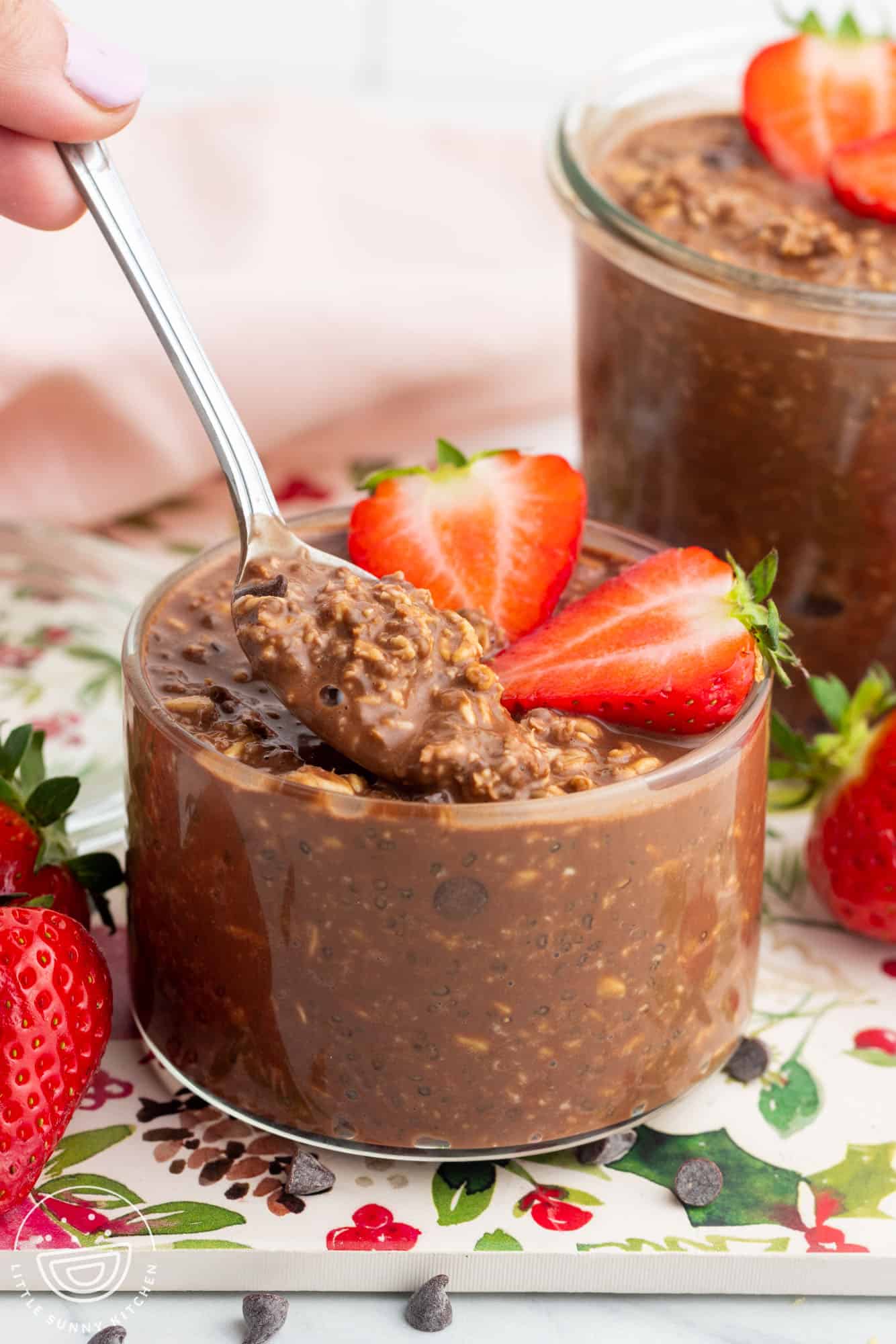 a short glass jar filled with chocolate overnight oats and topped with fresh strawberries.