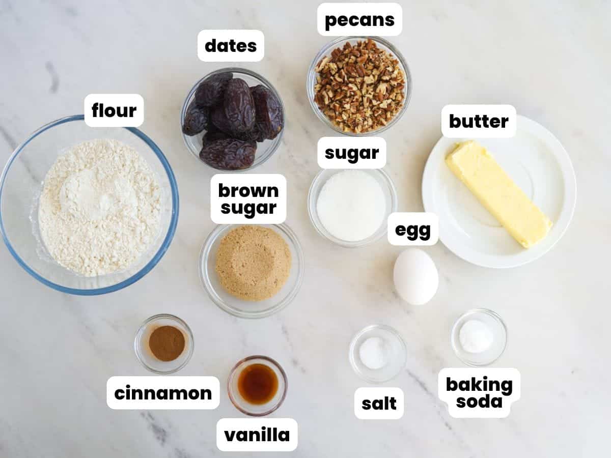 the ingredients for making date cookies, all measured out and in small bowls, arranged on a counter.