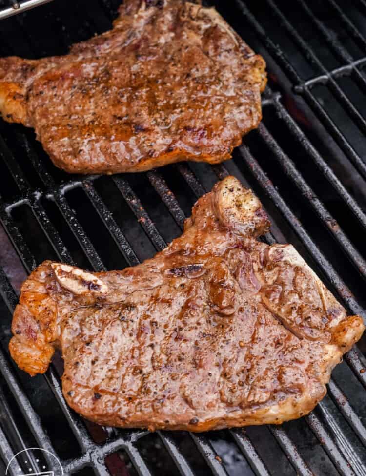 Two cooked T bone steaks on a grill.