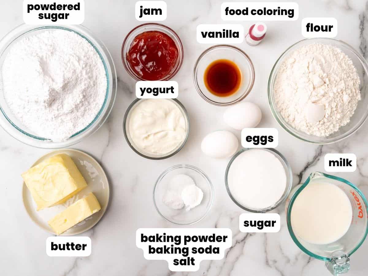 The ingredients needed to make vanilla cupcakes filled with jam from scratch. Each ingredient is already measured and shown in a separate bowl.