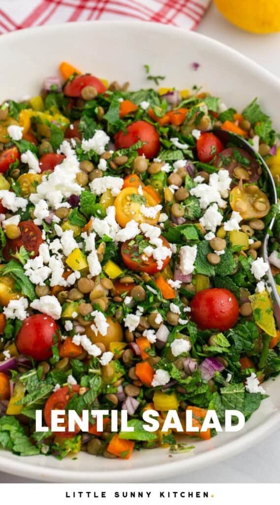 a white bowl of lentil salad topped with feta cheese.