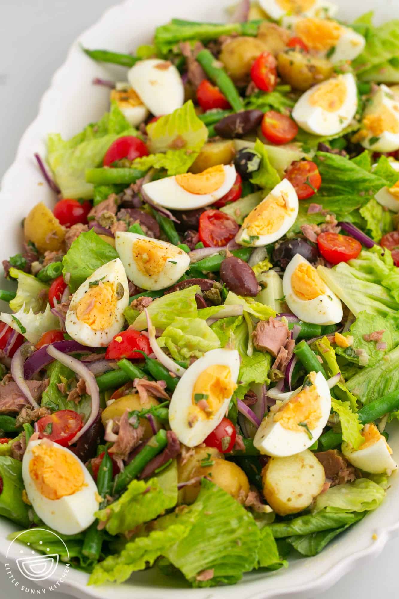 nicoise salad that has been tossed and served on a platter.