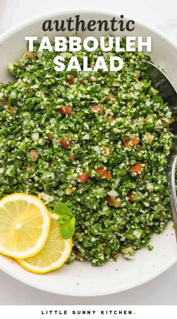 a large bowl of traditionally made tabbouleh salad with lemon slices on the side.