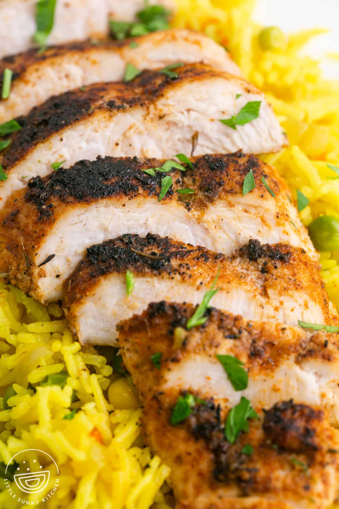 Sliced blackened chicken served over yellow rice
