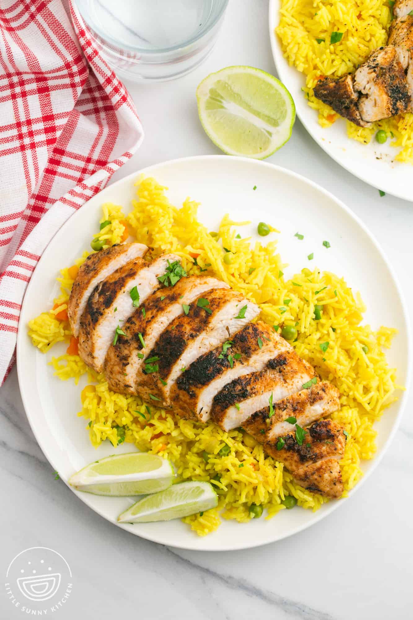 Sliced blackened chicken breast served over yellow rice with lime wedges