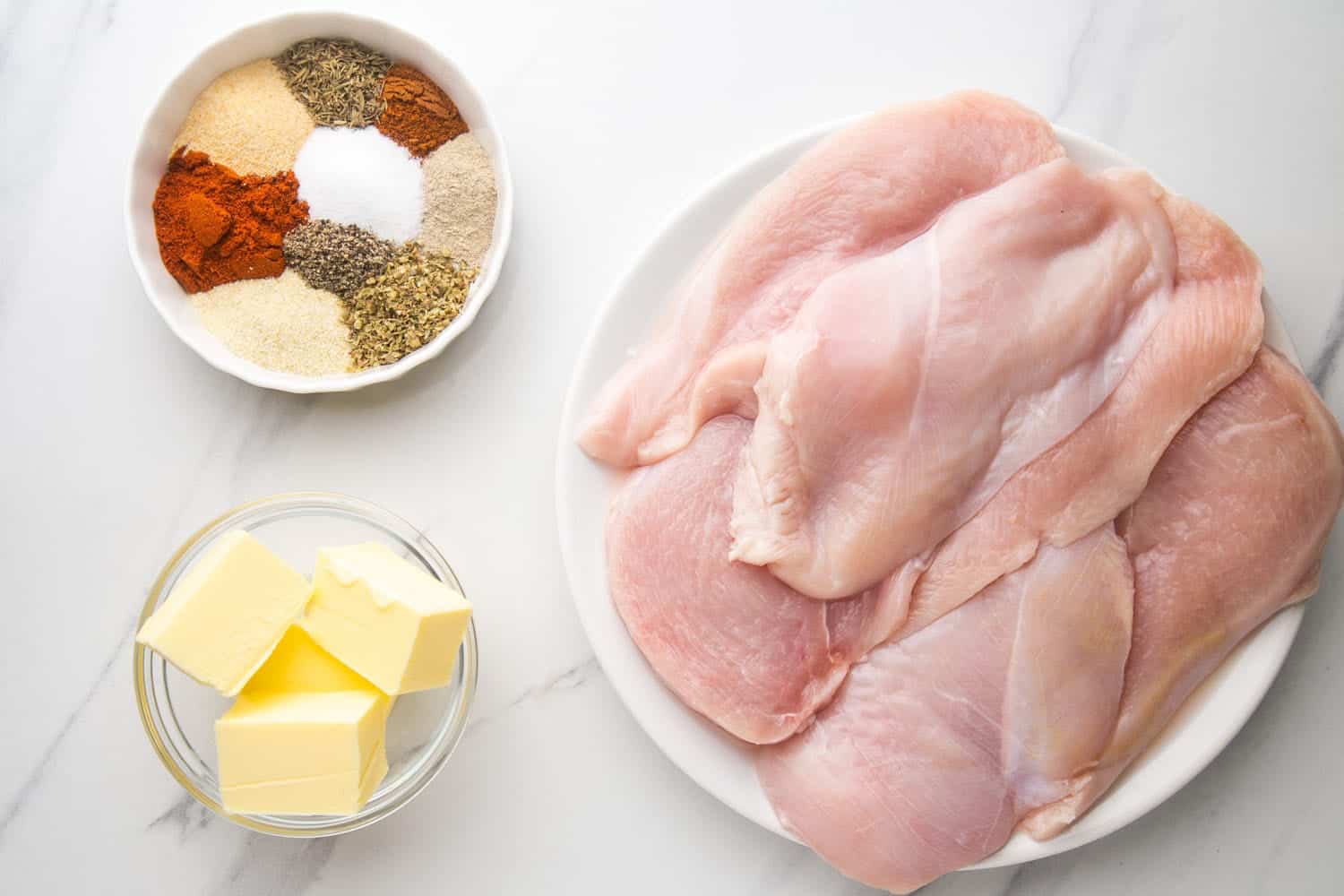 Ingredients needed for making blackened chicken including chicken cutlets, spices, and butter.