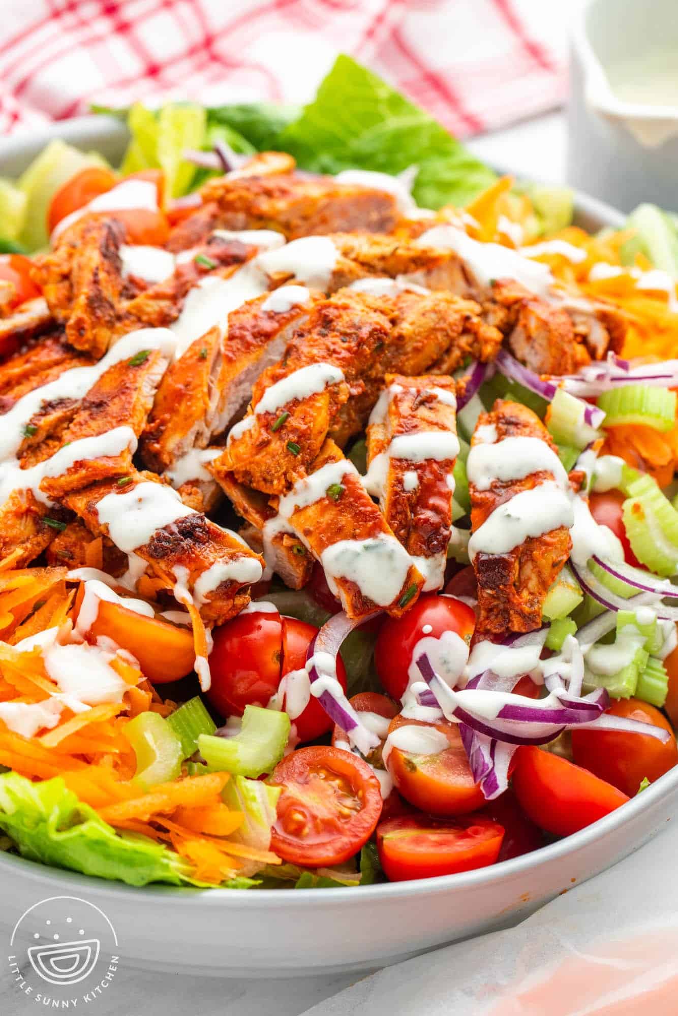 Unbreaded chicken on top of a buffalo chicken salad, drizzled with ranch dressing. 