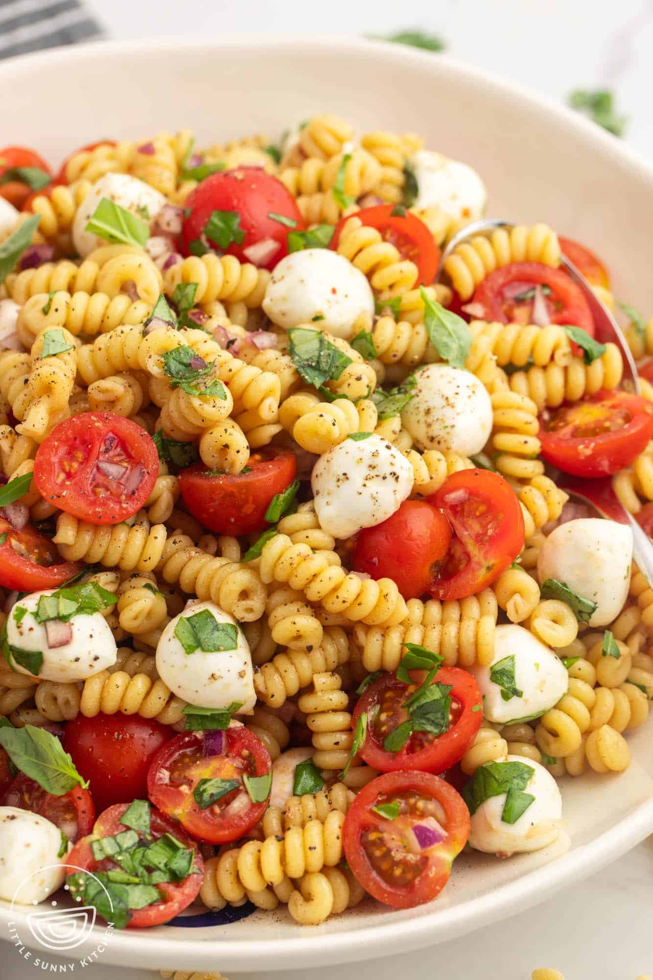 fusilli pasta salad with caprese tomatoes, basil, and mozzarella pearls. 