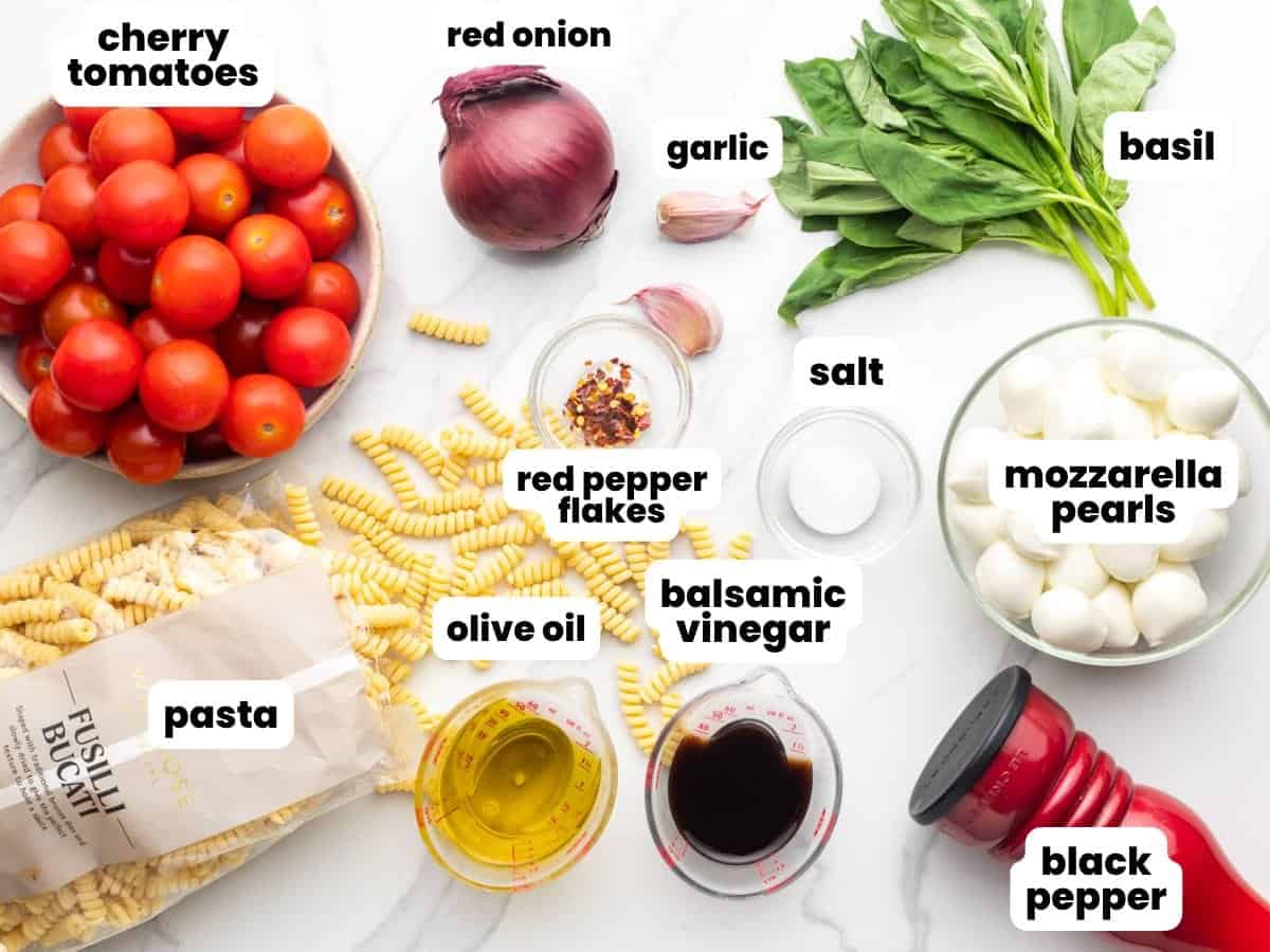 The ingredients needed to make caprese past salad arranged on a counter, viewed from above
