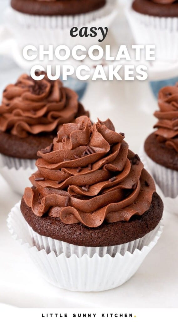 Chocolate cupcakes with chocolate buttercream frosting on a white marble board. And overlay text that says "easy chocolate cupcakes"
