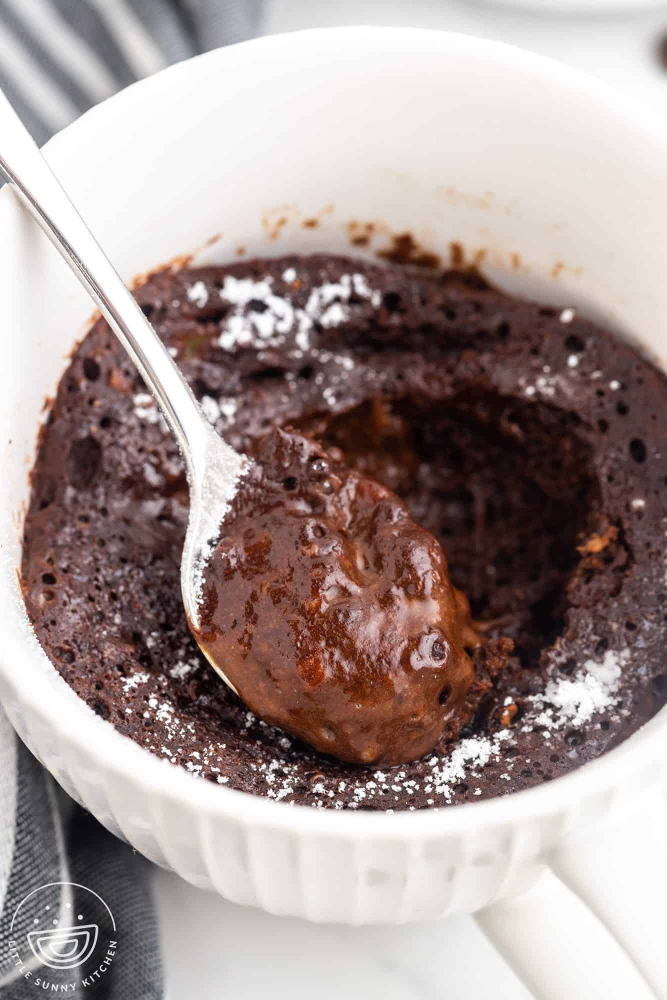 Overhead shot with an angle of chocolate lava mug cake and a spoon showing the soft center
