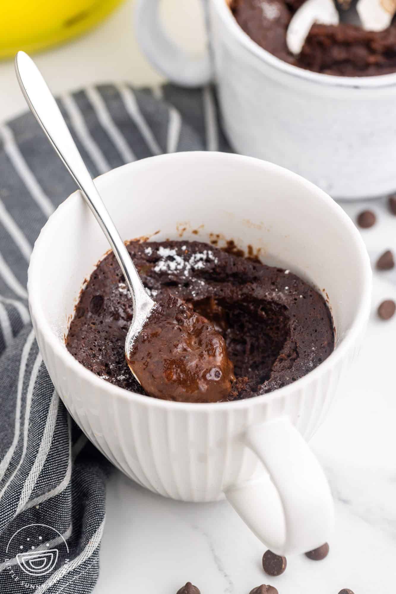 Angle shot of chocolate lava cake in a white mug and a spoon