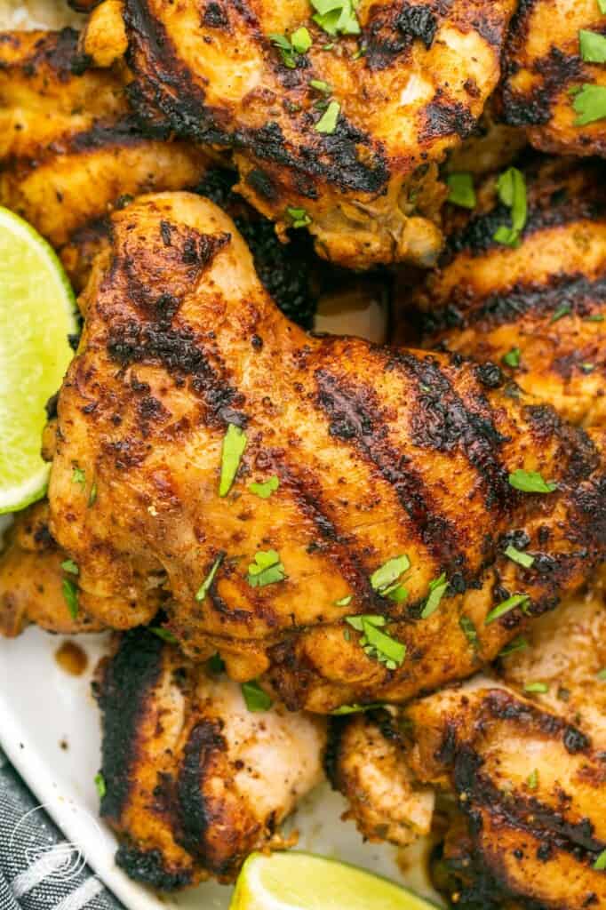 Boneless chicken thigs, grilled, garnished with lime and cilantro.