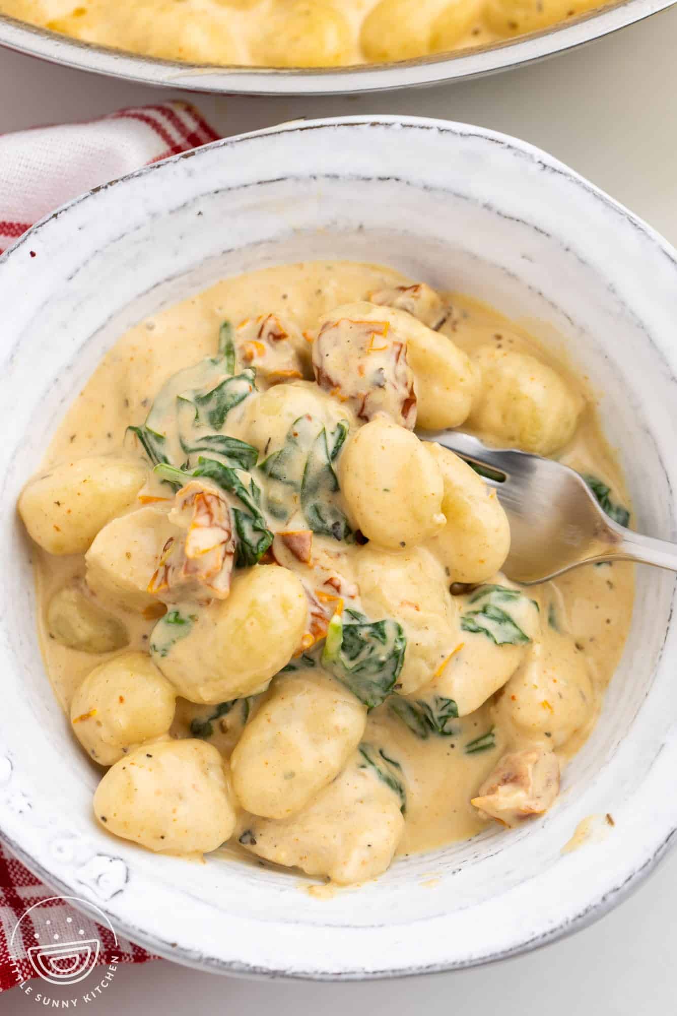 a bowl holding a serving of creamy gnocchi with chicken.