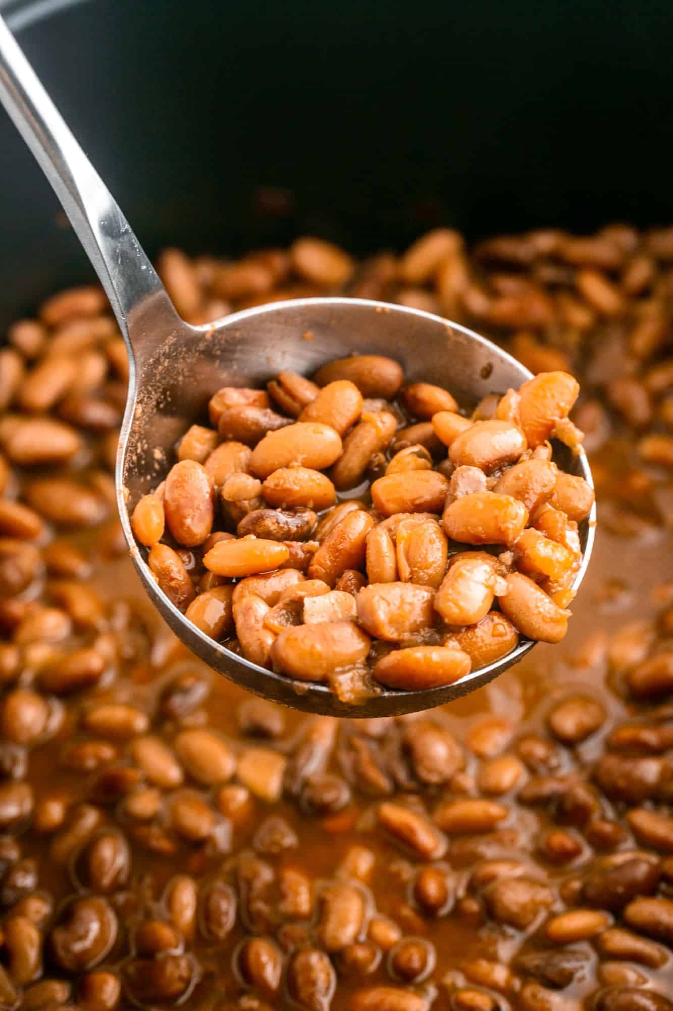 Ladle with cooked pinto beans over a crockpot