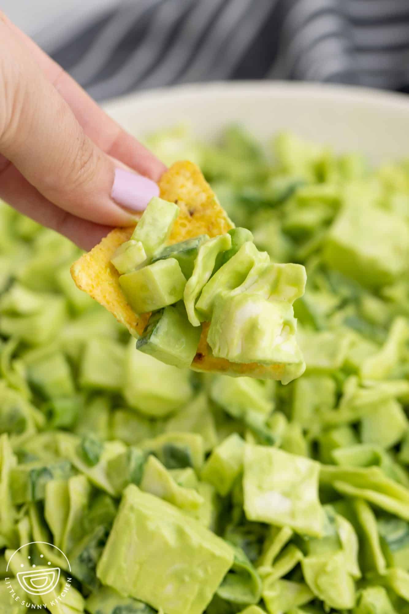 Holding a tortilla chip with green goddess salad, serving just like salsa