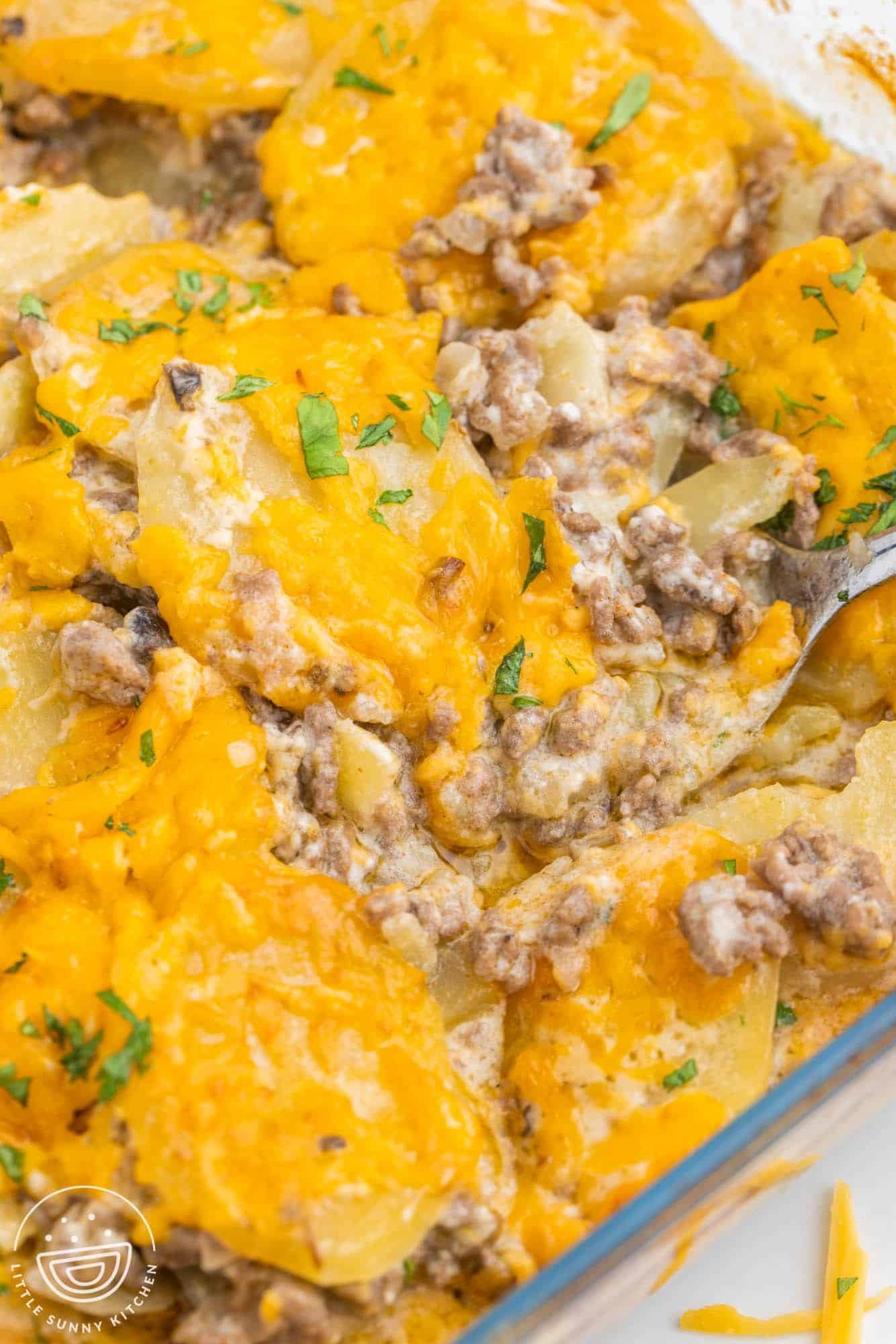 a spoon serving ground beef potato casserole from the pan.
