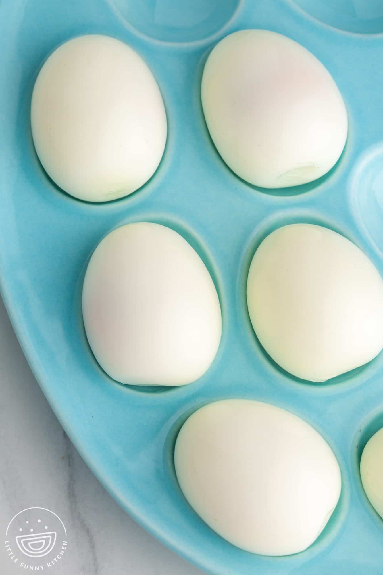 Overhead shot of hard boiled and peeled eggs on a blue plate