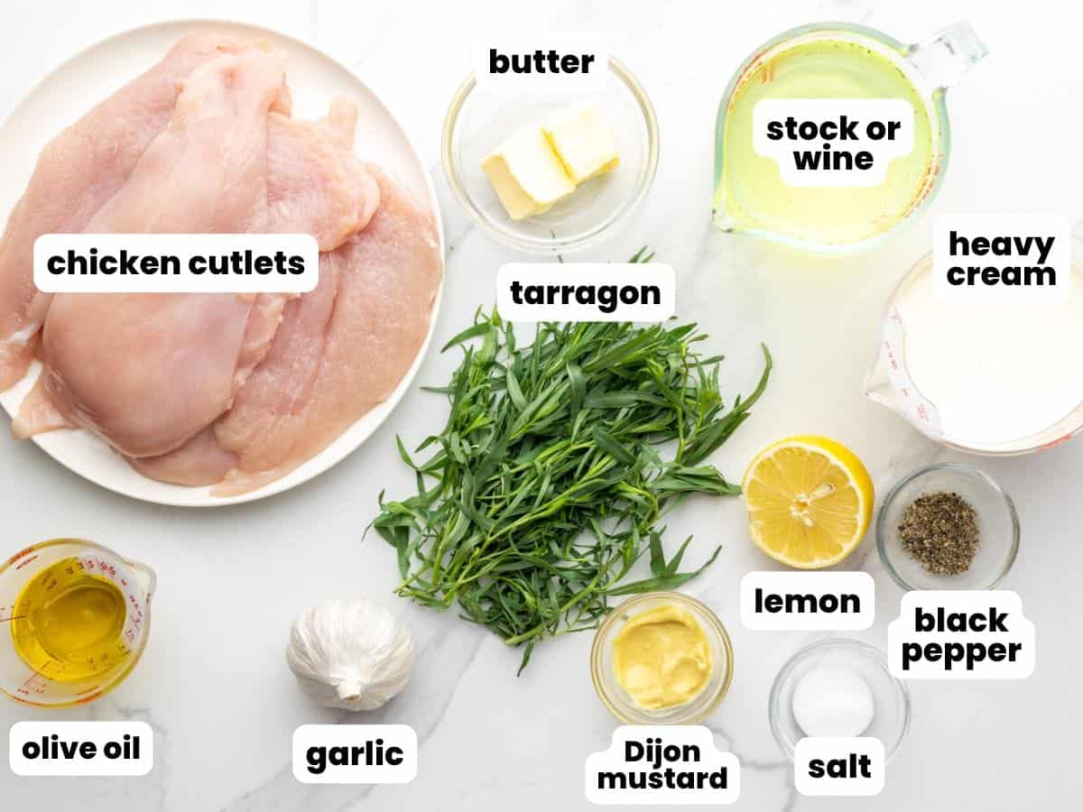 the ingredients for tarragon chicken, arranged on a counter and viewed from above, including fresh herbs, chicken cutlets, and seasonings.