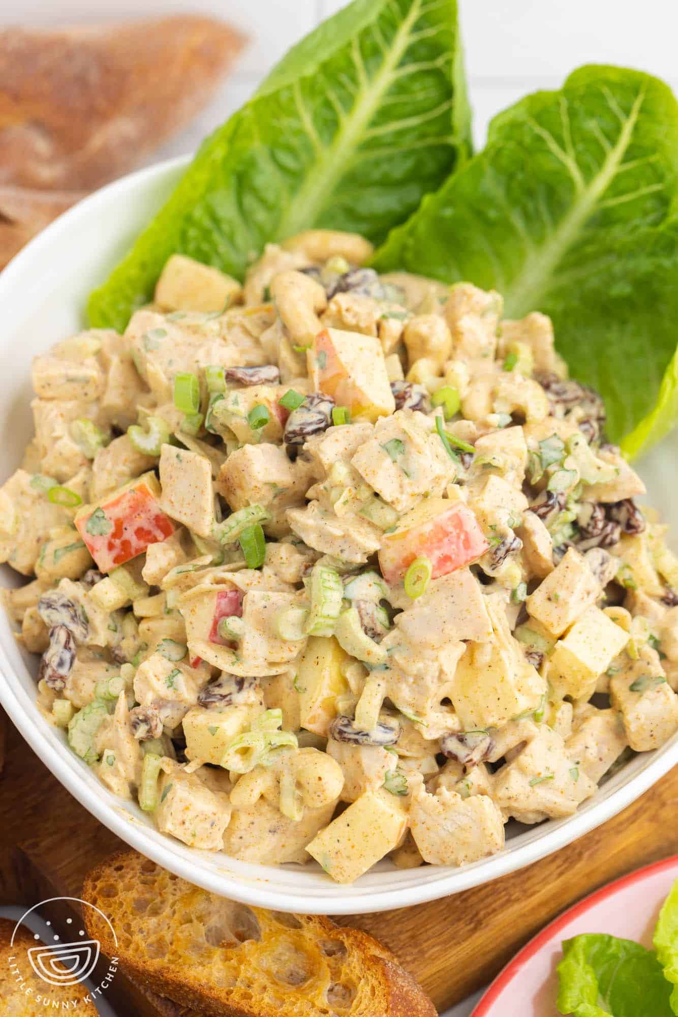 romaine leaves in a bowl filled with curry chicken salad.