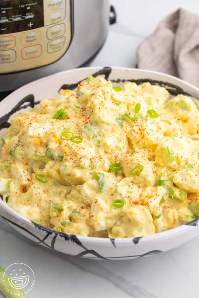 a large bowl of creamy potato salad in front of an instant pot.