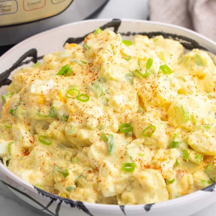 a large bowl of creamy potato salad in front of an instant pot.