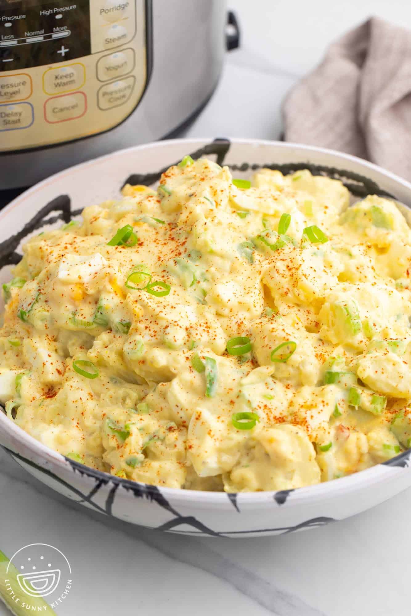 a large bowl of creamy potato salad in front of an instant pot. 