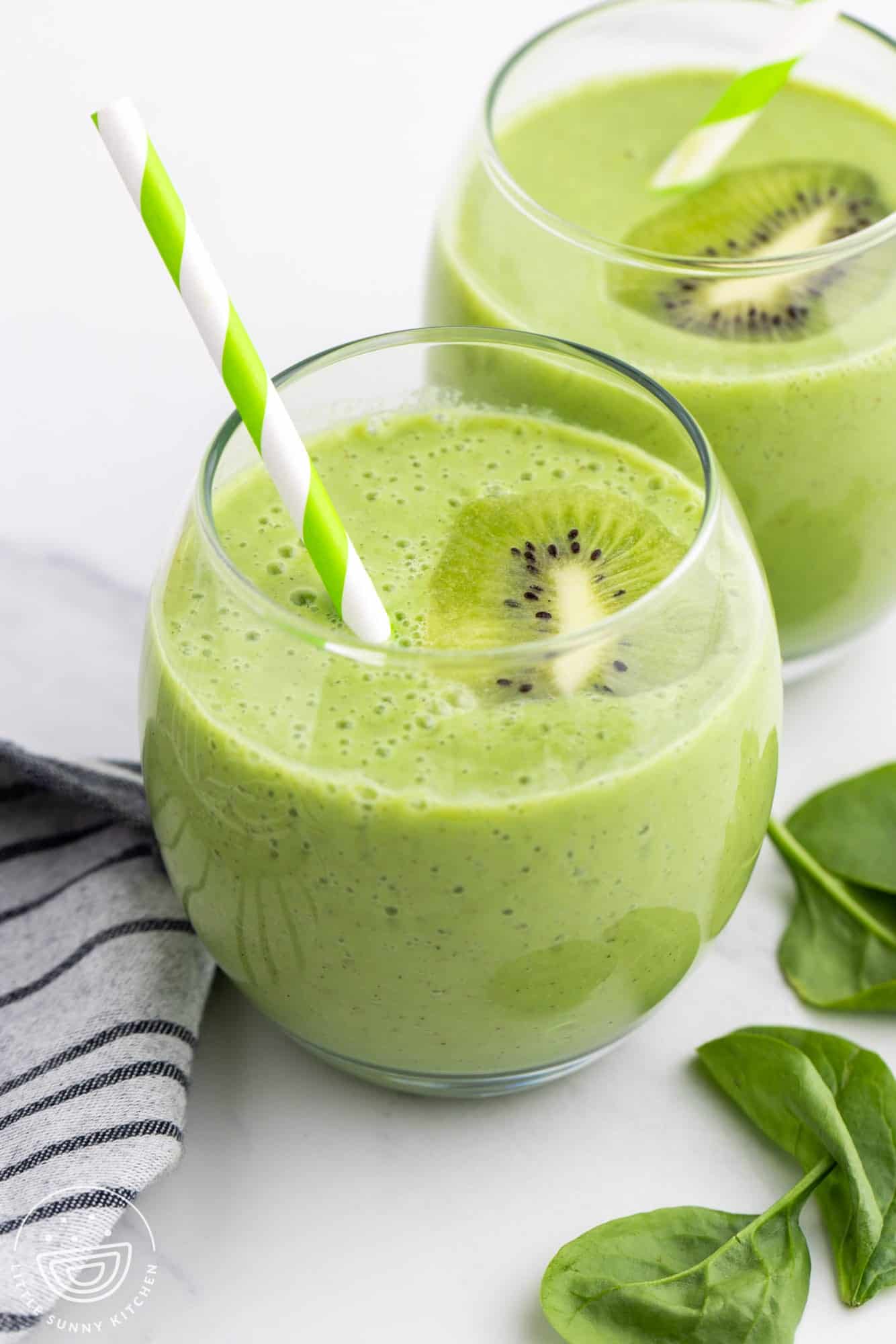 2 glasses of vibrant green kiwi smoothies, with green straws