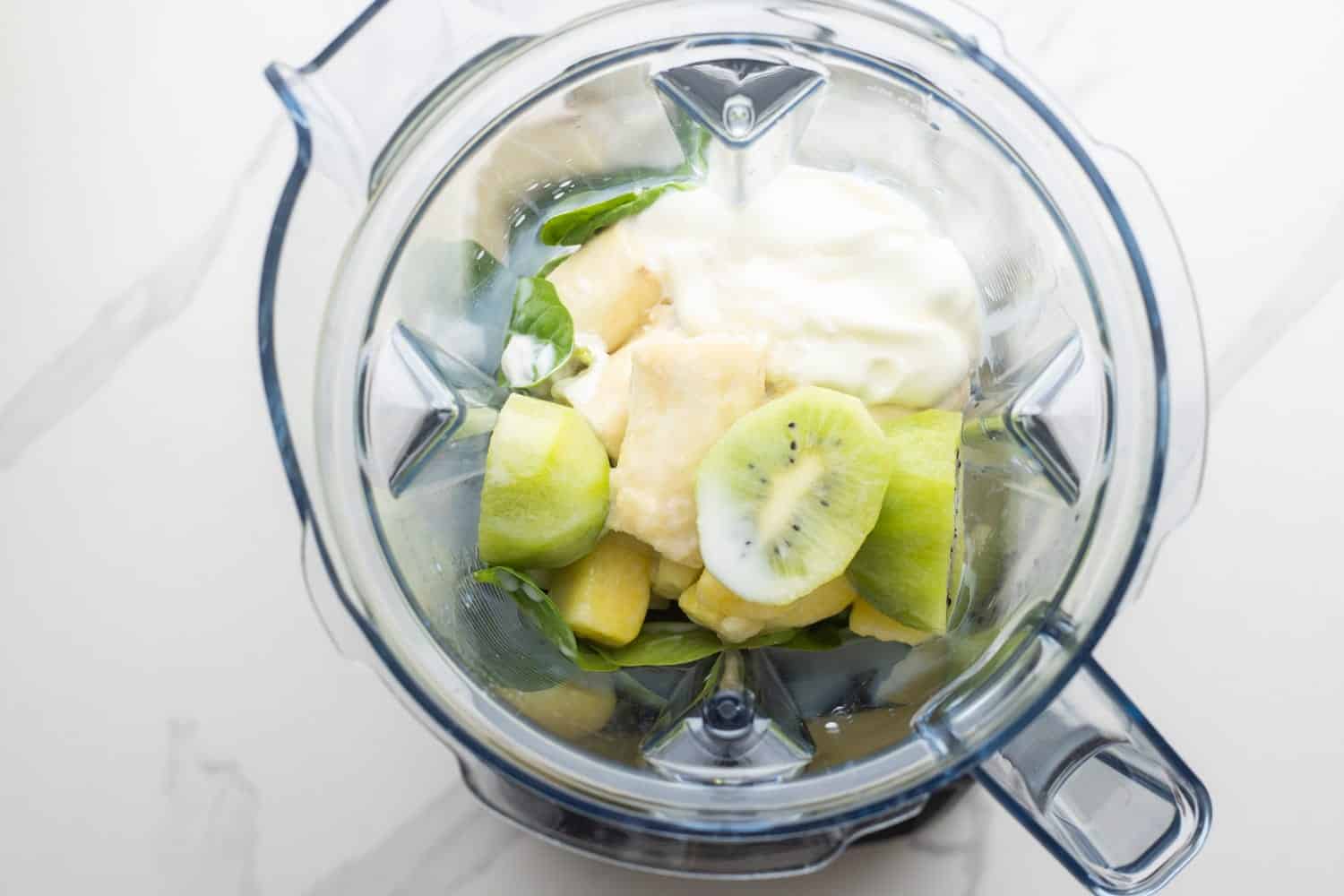 Kiwi smoothie ingredients in a blender jug before blending