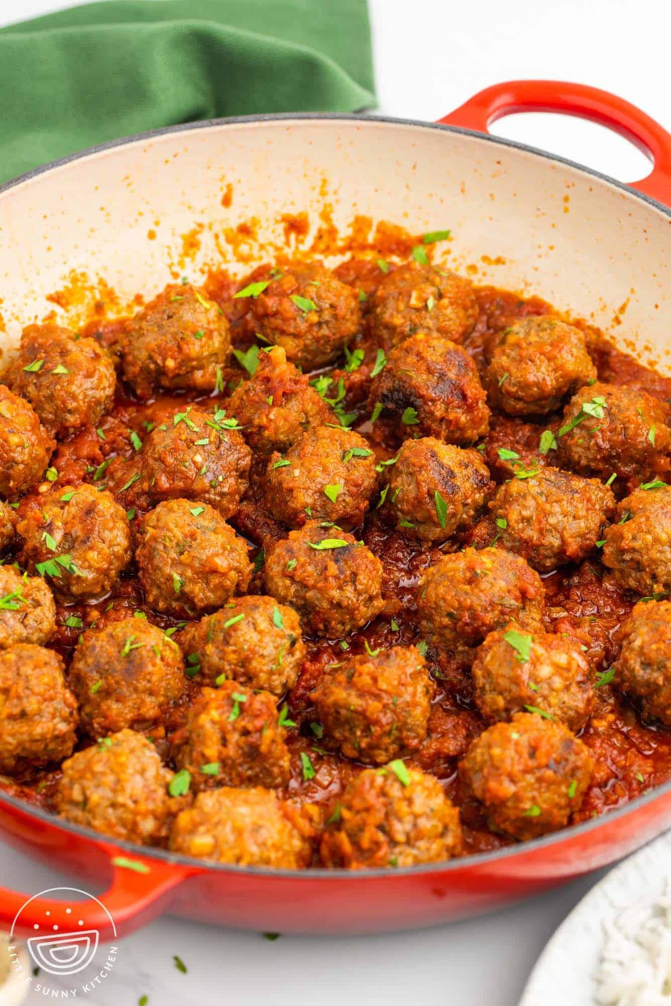 a red and white skillet with meatballs in it.