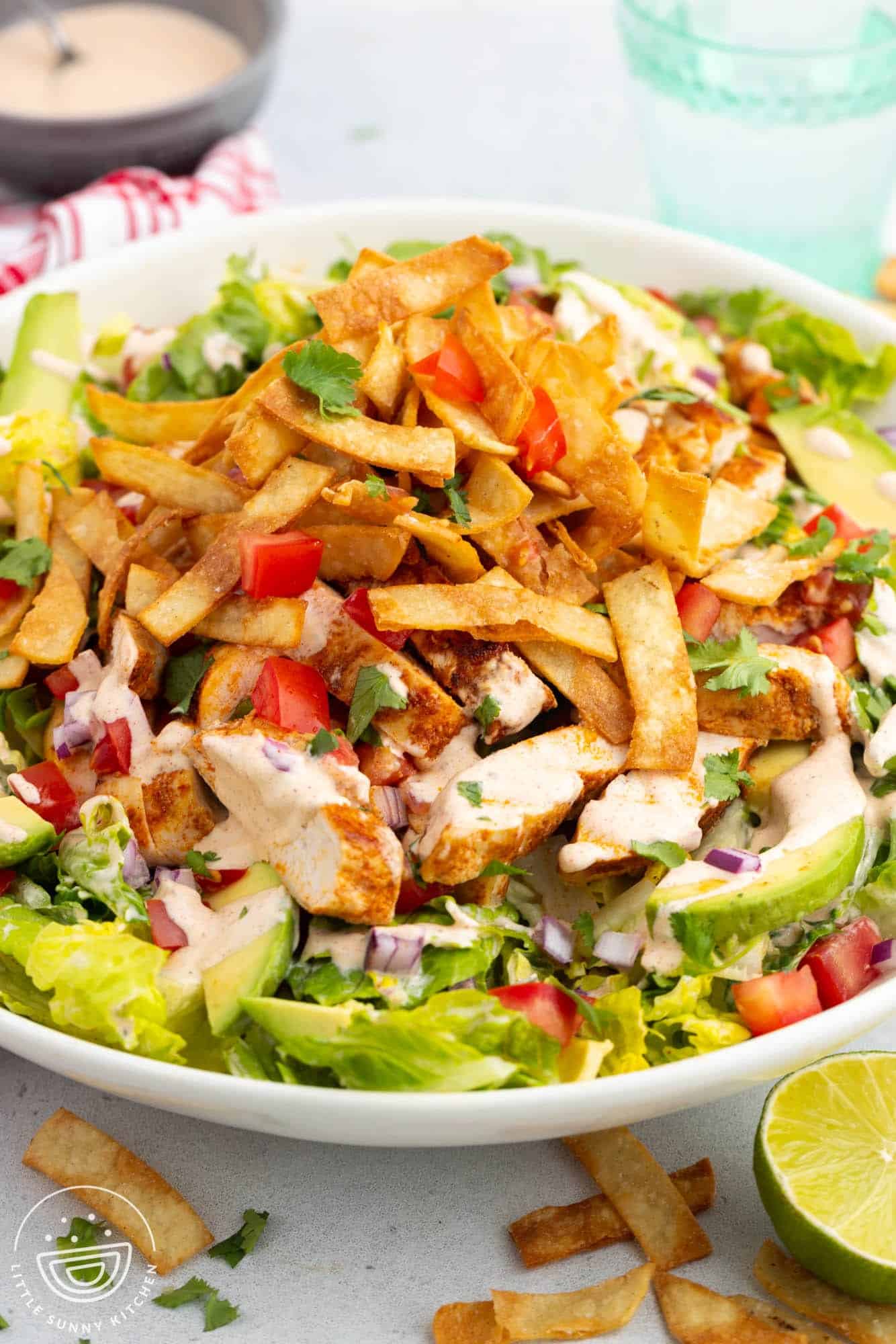 a large bowl of salad with santa fe chicken and tortillas.