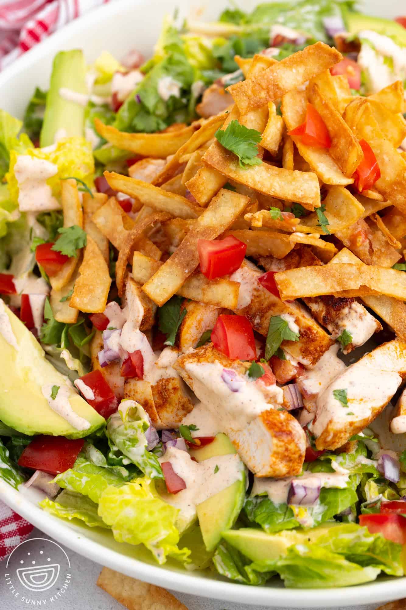 closeup of a copycat chili's santa fe salad with crispy tortilla strips and avocado.